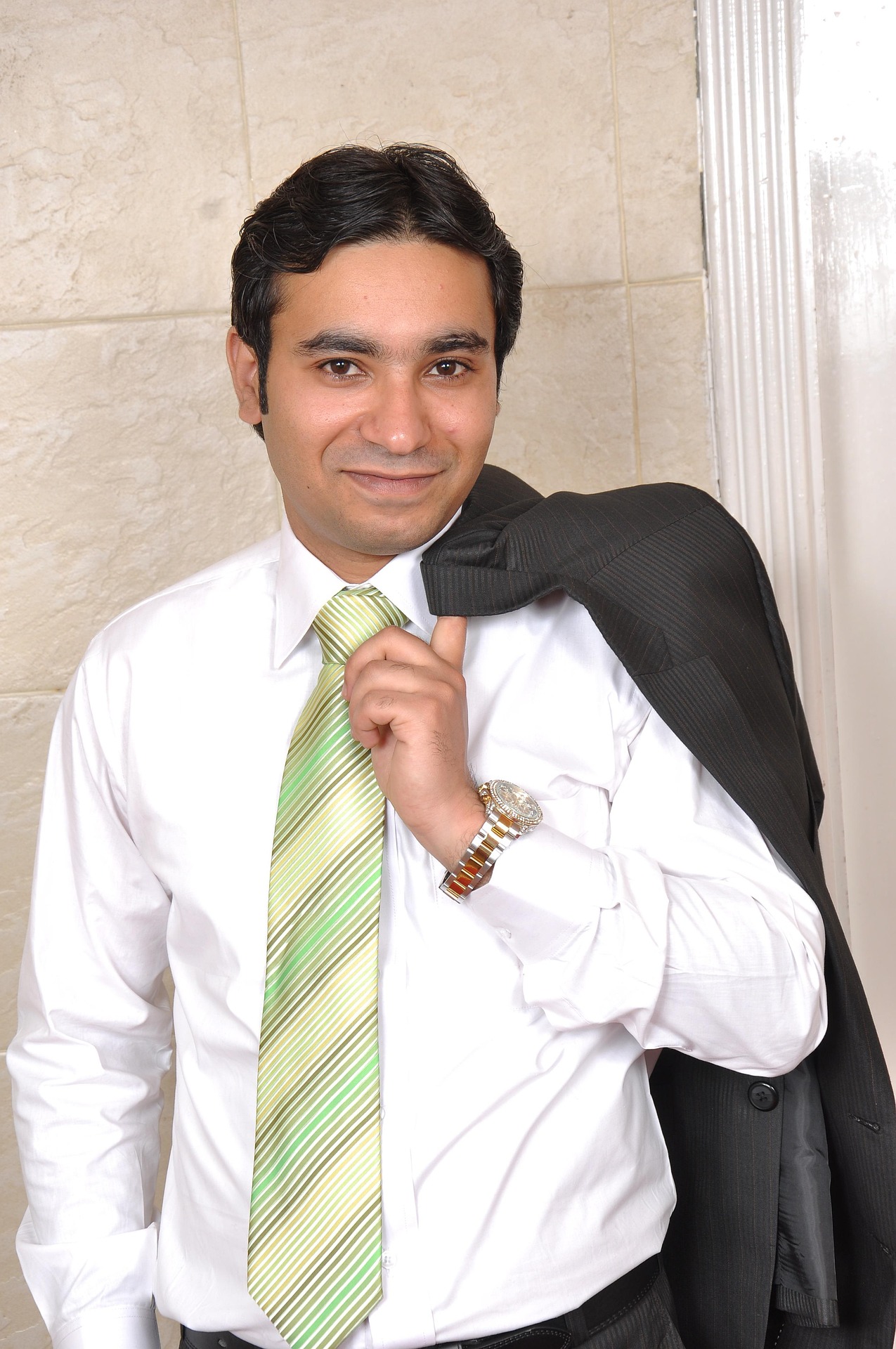 Guy wearing a white shirt with a light green tie and has a jacket over his shoulder